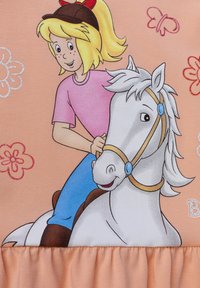 Rosa Stoff mit einem grafischen Motiv eines Mädchens in einem rosa Hemd, das auf einem grauen Pferd reitet. Der Hintergrund ist mit blumen- und schmetterlingsmotiven in hellen Farben gestaltet.