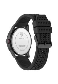 Black rubber strap watch with a stainless steel case, featuring a round shape, textured band, and water-resistant back, marked with the brand "Guess."