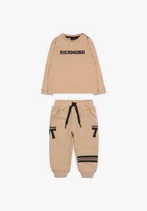 Beżowa koszula z długim rękawem z napisem "RICHMOND" w czerni, uzupełniona o pasujące spodnie dresowe z kieszeniami i czarnymi paskami.