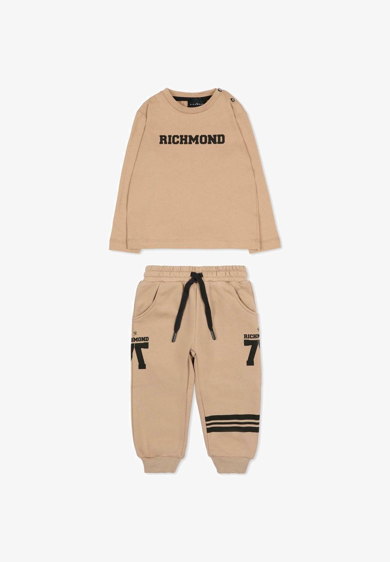 Maglietta beige a maniche lunghe con la scritta "RICHMOND" stampata in nero, abbinata a pantaloni della tuta dello stesso colore con tasche e dettagli a righe nere.