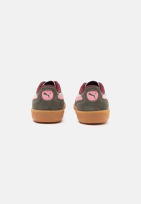 Zapatillas Puma con parte superior de ante gris, acentos en burdeos y un logo rosa. Presentan una suela de goma marrón y un acolchado texturizado en el talón.