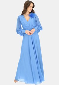 Niebieska maxi sukienka z lekkiego materiału, z długimi, plisowanymi rękawami, głębokim dekoltem w kształcie V oraz piórowym akcentem na lewym ramieniu.