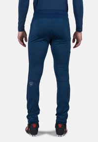 Navy urheiluhousut, joissa on muotoon ommeltu malli, joustava vyötärönauha ja sivutaskut. Ominaisuuksiin kuuluu logotehoste vasemmassa lahkeessa ja teksturoitu kangas.