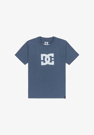 Camiseta de algodón azul con un gran logo blanco de DC que incluye una estrella, mangas cortas, cuello redondo y dobladillo recto. Sin patrones ni acentos.