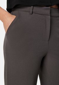 Pantalons gris ajustés en tissu lisse et texturé. Dotés d'une poche avant et d'un design épuré et structuré.