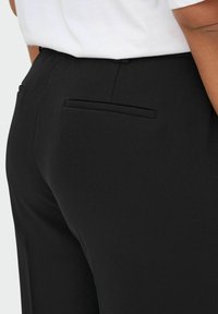 Pantaloni neri su misura realizzati in tessuto liscio, con una tasca sul retro e un design elegante e contemporaneo con taglio dritto.