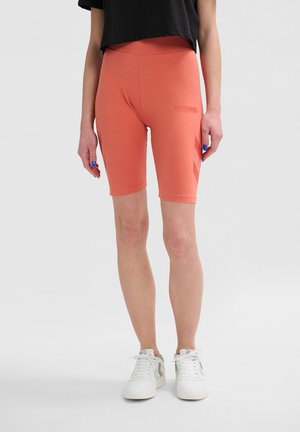 Pfirsichfarbene Radfahrshorts aus dehnbarem Material, mit einem hohen Bund und einem dezenten Logoaufdruck an der Seite.