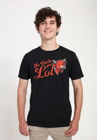 Černé tričko s potiskem "La Vache qui Lol" a grafikou usmívající se krávy. Krátké rukávy, kulatý výstřih, měkká textilie.