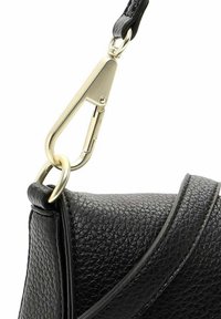 Bolso cruzado de cuero negro con un acabado texturizado, que presenta un clip y un anillo de metal en tono dorado, y un detalle en la correa.