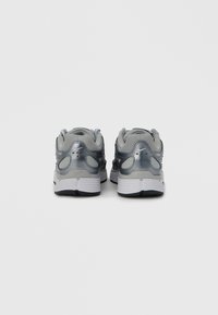 Γκρι αθλητικά παπούτσια με επάνω μέρος από δίχτυ, γυαλιστερές γκρι λεπτομέρειες, επενδεδυμένο κολάρο και λευκή ενδιάμεση σόλα· σταθερό τακούνι με λεπτομέρειες εξαερισμού.