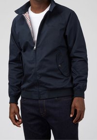 Navy bomber jacket in synthetic material, features a zip front, two side pockets, ribbed cuffs, and a checkered inner lining.