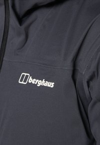 Veste gris foncé avec une texture lisse, dotée d'une fermeture éclair à l'avant et d'un logo "Berghaus" blanc au niveau de la poitrine.