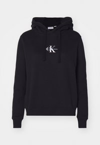 Felpa nera in morbido cotone con tasca frontale. Caratterizzata da un logo bianco di Calvin Klein Jeans sul petto e cappuccio regolabile con cordino.
