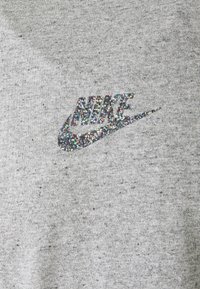 Šedá mikina s flekatou texturou; obsahuje třpytivou značku Nike z vícebarevných flitrů.