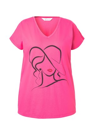 Růžové bavlněné tričko s výstřihem do V, volný střih. Má černý návrh line-art obličeje, zvýrazněný červenými rty a kroužkovými náušnicemi.