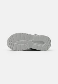 Semelle de chaussure avec un design texturé et robuste. Principalement en caoutchouc blanc avec un motif en zigzag, offrant adhérence et stabilité.