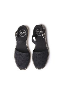 Svarta espadrillosandaler med vävd textur, justerbar ankelrem och en naturlig jutesula. Har dekorativ sömnad längs kanterna.