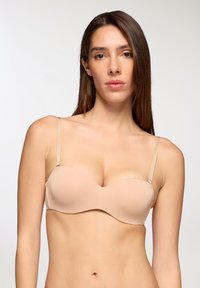 Reggiseno color beige senza spalline con coppe lisce e imbottite, spalline sottili regolabili e design senza cuciture, adatto da indossare sotto abiti aderenti.