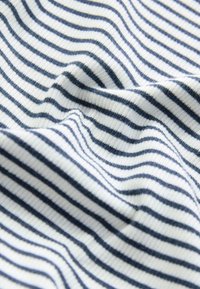 Tissu en coton à texture lisse, présentant des rayures étroites alternées bleu marine et blanches, créant un motif rythmique sur toute la surface.