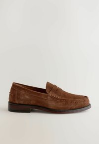 Mocasines de ante marrón con puntera redondeada, costura decorativa en la parte superior y un tacón bajo. Textura suave y diseño minimalista.