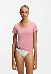 Lyserød T-shirt med korte ærmer og rund halsudskæring, glat tekstur og slank pasform. Let cropped design; logodetalje på kanten.