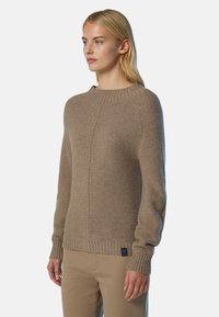 Beige gestrickter Pullover mit rundem Halsausschnitt, gerippten Bündchen und einem strukturierten Stickmuster. Mit einem kleinen Logostickat an dem Saum.