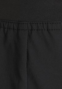 Schwarzer Stoff mit glatter Textur, der an der oberen Kante mit gerafftem Stich versehen ist und an der Seite eine flache Naht aufweist.