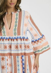 Abito boho multicolore in lino con scollatura a V profonda, maniche a campana e motivi intricati di strisce, diamanti e soli.