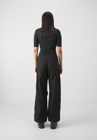 Pantalons larges noirs à taille haute avec une texture subtile, associés à un haut noir ajusté à manches courtes. Pas de motifs visibles ni de matériel.