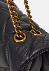 Svart quiltad läderväska med guldkedjehandtag och metallringar. Har en slät textur och märkessymboler, vilket framhäver hållbarhet och stil.