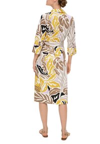 Robe portefeuille fleurie avec un col, des manches courtes et une ceinture à la taille. Présente de grands motifs de feuilles jaunes, noires, brunes et lavande sur un fond lumineux.