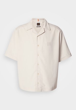 Chemise à manches courtes, en crème, à boutons, fabriquée en tissu lisse, avec une petite poche avec logo carré et un design de col classique.