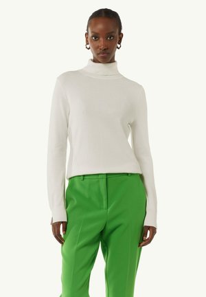 Maglione bianco a collo alto in un morbido tessuto a maglia, abbinato a pantaloni verdi su misura. Presenta maniche lunghe e una vestibilità rilassata.