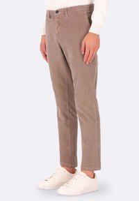 Pantaloni in corduroy marrone con righe verticali, slim fit, dotati di chiusura con bottone e tasche laterali, abbinati a sneakers bianche.