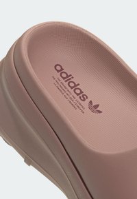 Rosa Adidas-Sandale mit glattem, rundem Design, strukturiertem Oberflächendetail, geprägtem Logo und dezenten Akzenten.