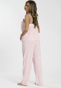 Conjunto de pijama rosa claro con finas rayas verticales y pequeños patrones florales. Incluye una parte superior sin mangas con tirantes atados y pantalones de corte holgado.