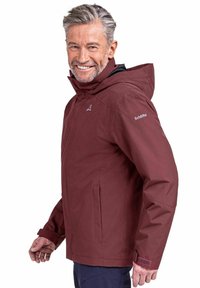 Bordeauxroter wasserdichter Jacke mit Kapuze, ausgestattet mit einem Reißverschluss vorne, Seitentaschen und verstellbaren Bündchen. Hergestellt aus strapazierfähigem Stoff mit glatter Oberfläche.