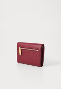 Portafoglio in pelle bordeaux con superficie testurizzata, dotato di una tasca con zip dorata e forma rettangolare. Design compatto per un'archiviazione minimalista.