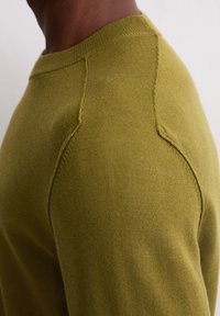 Olijfgroen trui van gebreid materiaal, met een ronde hals, raglanmouwen en een gladde textuur met verstevigde naden.