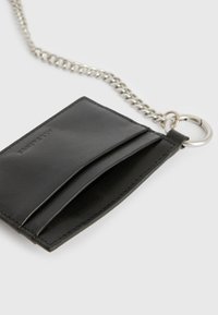 Zwarte leren kaarthouder met twee sloten, bevestigd aan een zilveren ketting en ring, met een gladde textuur en nette stiksels.