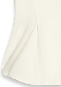 Top color crema realizzato in tessuto morbido, con orlo arrotondato e fessure laterali per facilitare i movimenti. Texture liscia con minimalismo nei dettagli.
