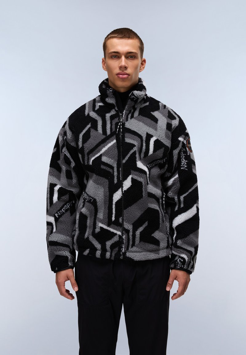 Giacca in fleece nera e grigia con motivi geometrici, colletto alto, zip frontale e tasche laterali. Design caldo e testurizzato.
