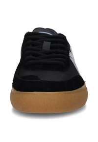 Sneaker nera con punta in suede testurizzato, tomaia in tessuto liscio e suola in gomma colorata. Include lacci neri prominenti e dettaglio del logo.