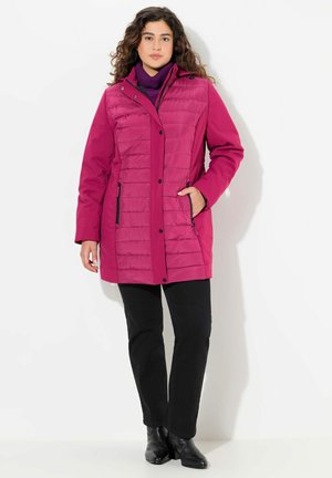 Fuchsia puffer jacket with vertical stitching, high collar, and two side pockets. Worn over a purple turtleneck, paired with black pants.