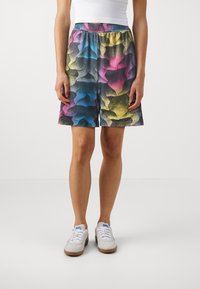 Vícebarevné šortky s geometrickým vzorem v modré, růžové, žluté a černé barvě, s elastickým pasem; doplněné o bílé tenisky.