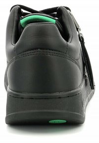 Zapatilla negra con un acabado de piel lisa, forma redondeada, acento verde en contraste en el acolchado del collar y suela de goma texturizada.