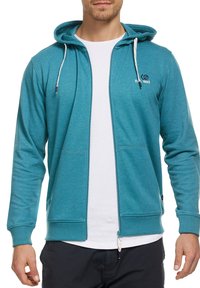 Sweat à capuche en tissu teal avec une finition texturée. Doté de cordons blancs, de poches avant et d'un petit logo sur la poitrine gauche.