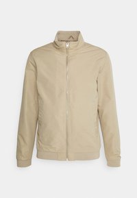 Giacca beige con zip e colletto alto, realizzata in tessuto liscio. Presenta polsini ed orlo elasticizzati, tasche laterali e cuciture minime.