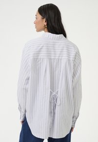 White and gray striped long-sleeve shirt with a back tie detail and subtle pleats, featuring a classic collar and relaxed fit.