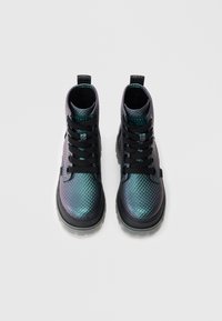 Violetas un zaļgani zāles zābaki ar melnām kurpju šņorēm, tiem ir fakturēts augšdaļa, mīkstināta zolīte un zīmola uzlīme uz mēles.